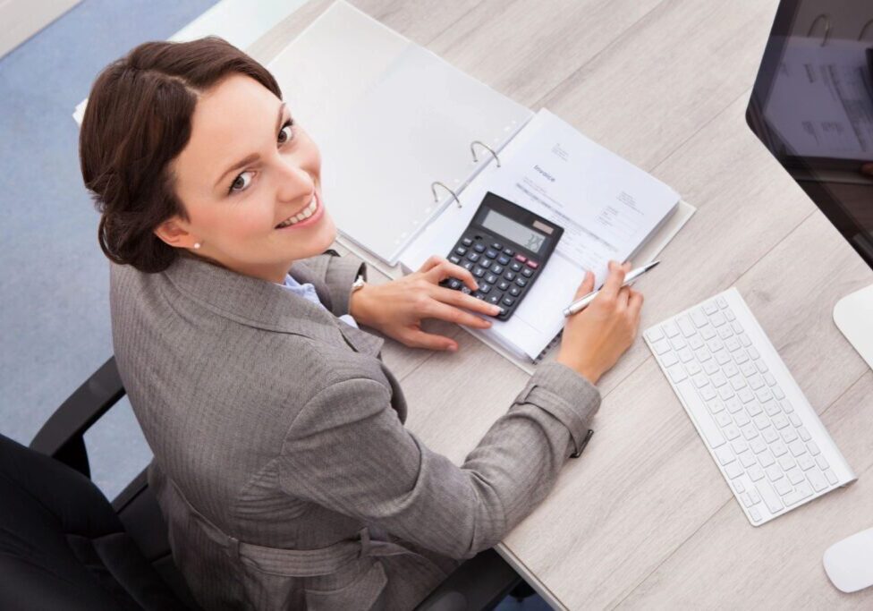 A woman sitting at a table with papers and a calculator.