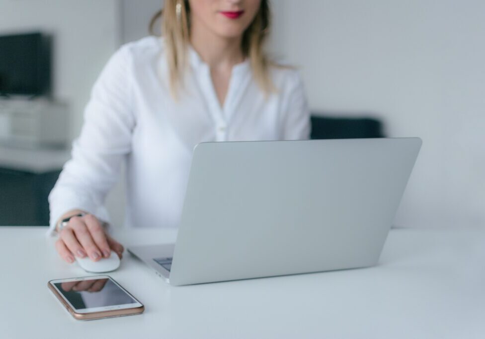 A woman sitting at a table with a laptop and mouse.